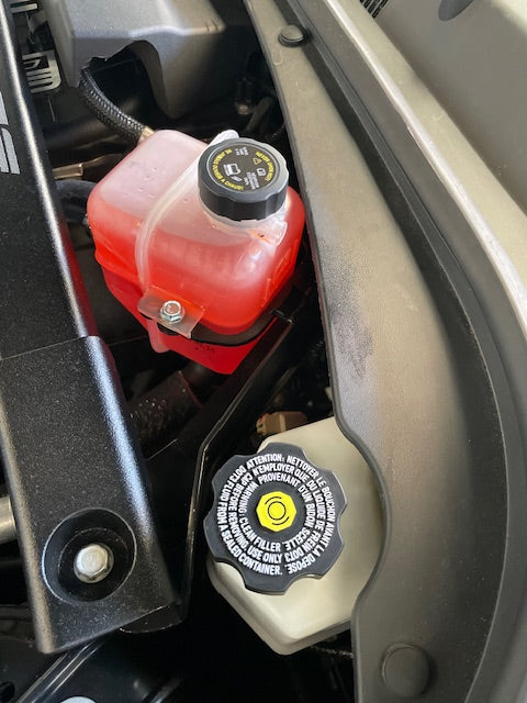 Close-up of a car's engine compartment with oil and coolant reservoirs.